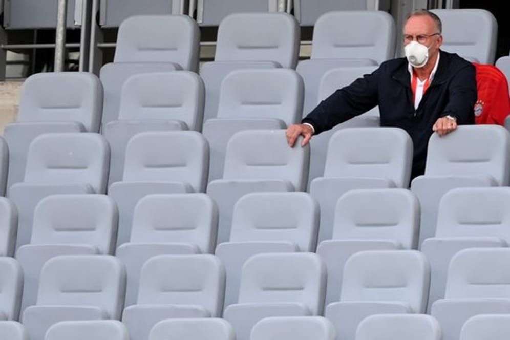 Karl-Heinz Rummenigge (l), Vorstandschef der FC Bayern München AG, sitzt auf der leeren Tribüne.