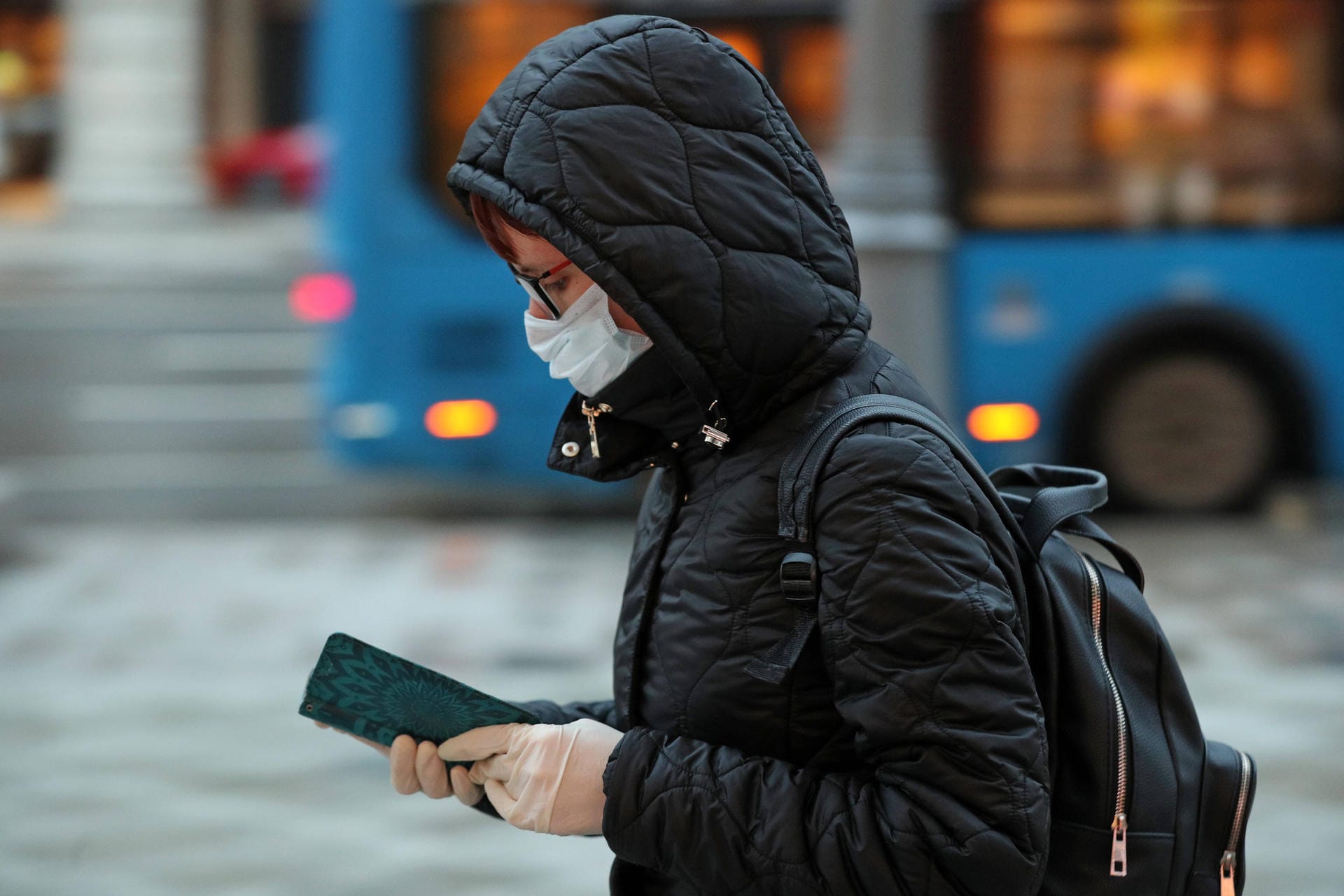 Eine Frau mit Maske und Smartphone: Sicherheitsexperten warnen vor falschen Corona-Warn-Apps