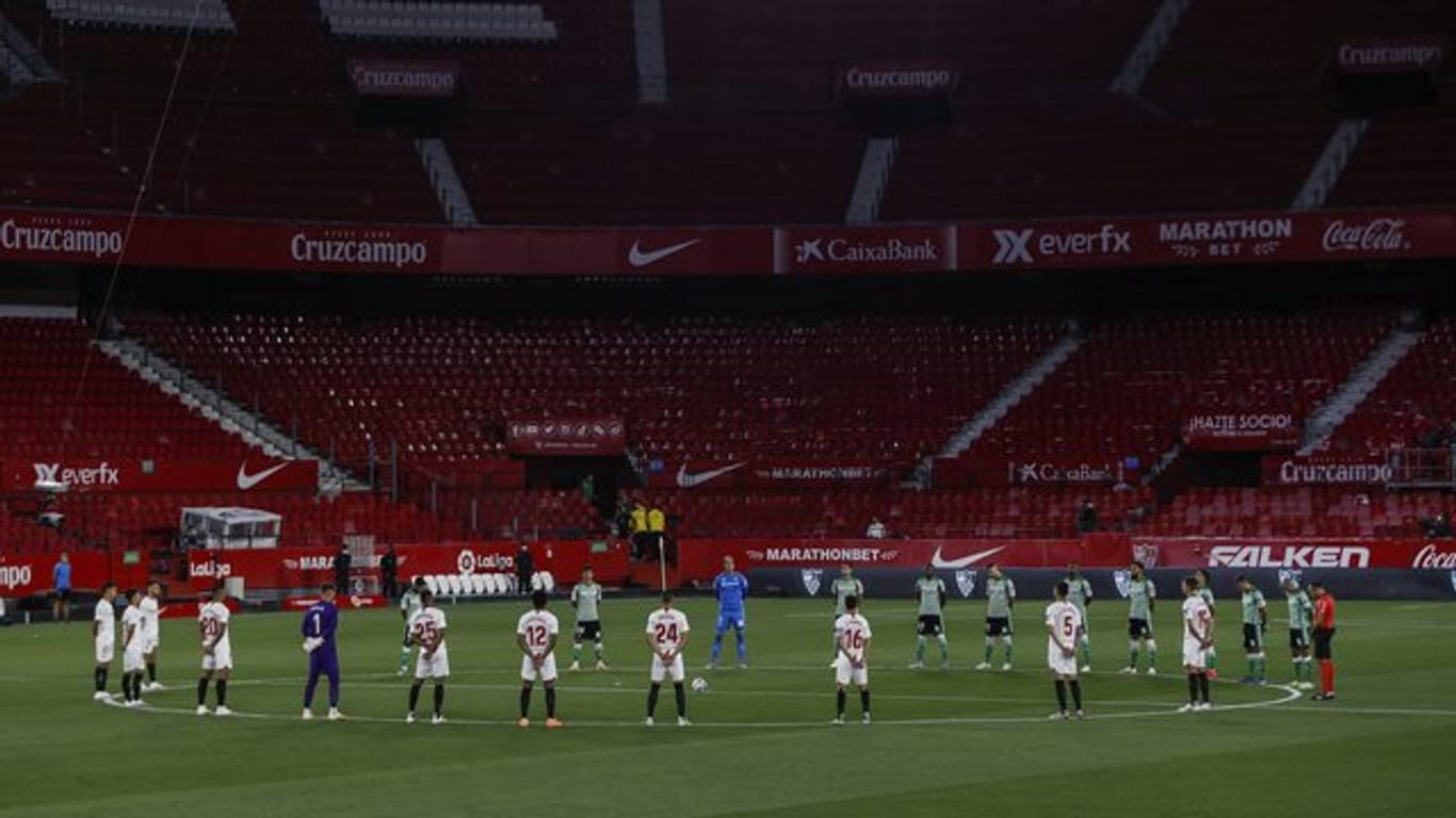 Spieler des FC Sevilla und Real Betis Sevilla legen eine Schweigeminute für die Coronavirus-Todesopfer ein.