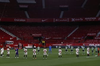 Spieler des FC Sevilla und Real Betis Sevilla legen eine Schweigeminute für die Coronavirus-Todesopfer ein.