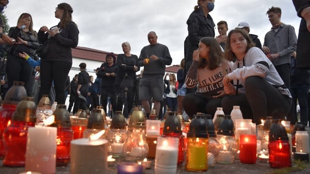 Menschen zünden Kerzen vor der Schule im Ort Vrutky an.