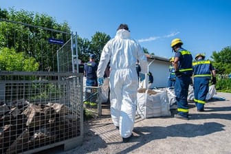 Mitarbeiter vom Technischen Hilfswerk (THW) tragen vor dem Abriss der Gartenlaube des Verdächtigen im Missbrauchsfall von Münster einen steinumrandeten Erdhügel ab.