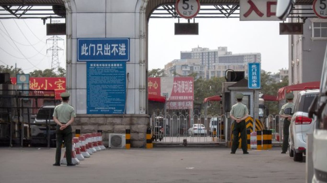 Polizisten halten vor den barrikadierten Eingängen des Xinfadi-Großmarktes Wache.