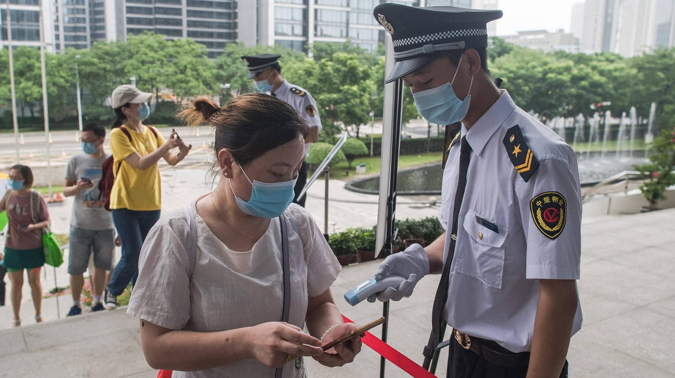 Corona-Kontrolle in Wuhan: Ein Beamter misst bei einer Frau Fieber.