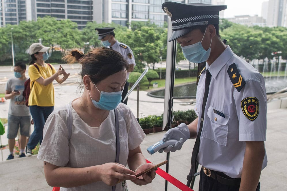 Corona-Kontrolle in Wuhan: Ein Beamter misst bei einer Frau Fieber.