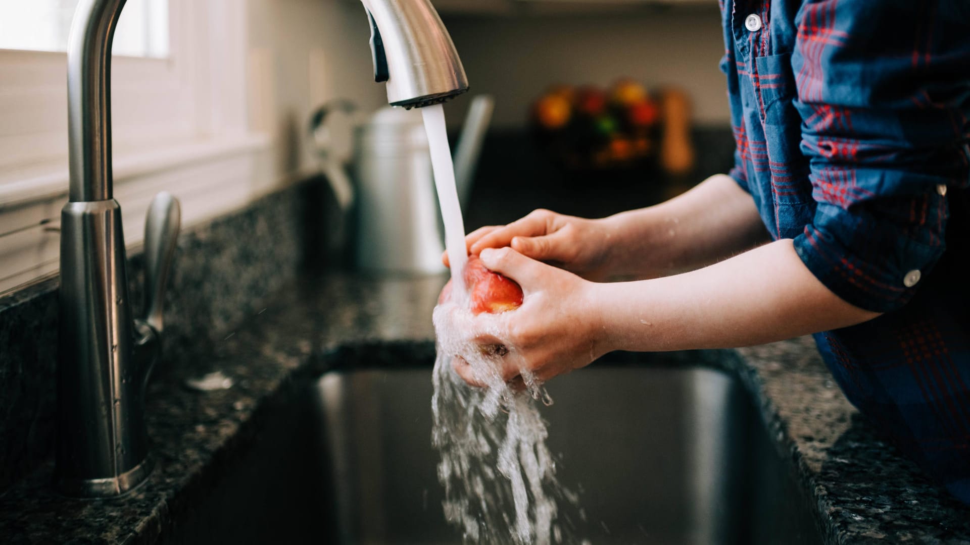 Kind wäscht Apfel: Durch die Klimakrise werden bei der Wasserversorgung auch in Deutschland Konflikte entstehen.