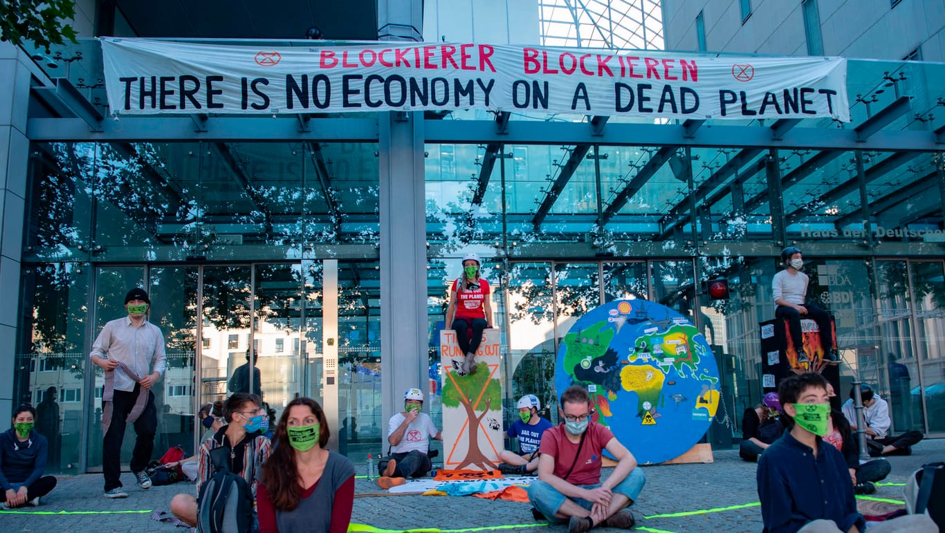 Aktivisten der Umweltschutzbewegung Extinction Rebellion (XR) sitzen vor dem Haus der Deutschen Wirtschaft in Berlin-Mitte: An dessen Gebäude wurde ein Bammer mit der Aufschrift «Blockierer blockieren - There is no economy on a dead planet" aufgehängt.