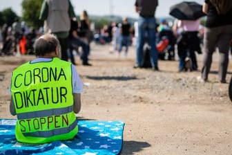 Ein Demonstrant trägt eine Warnweste mit der Aufschrift "Corona Diktatur stoppen": In Deutschland kursieren einige Verschwörungstheorien zum Coronavirus.