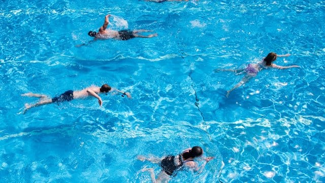 Die Besucher eines Freibads schwimmen im Becken