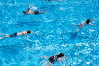 Die Besucher eines Freibads schwimmen im Becken