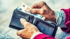 Die Hände einer Rentnerin holen Geldscheine aus einer Brieftasche (Symbolbild). Das Rentenniveau in Deutschland liegt bei rund 48 Prozent.