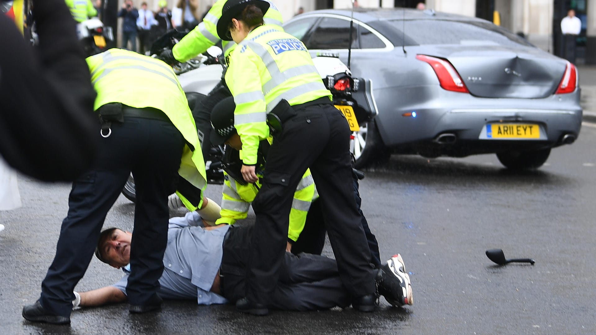 Kurz nach dem Unfall: Polizisten nehmen den am Boden liegenden Demonstranten fest, die Heckklappe von Johnsons Auto ist stark eingedrückt.