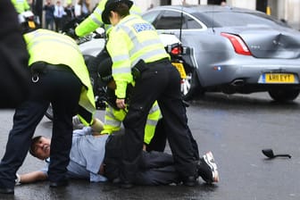 Kurz nach dem Unfall: Polizisten nehmen den am Boden liegenden Demonstranten fest, die Heckklappe von Johnsons Auto ist stark eingedrückt.