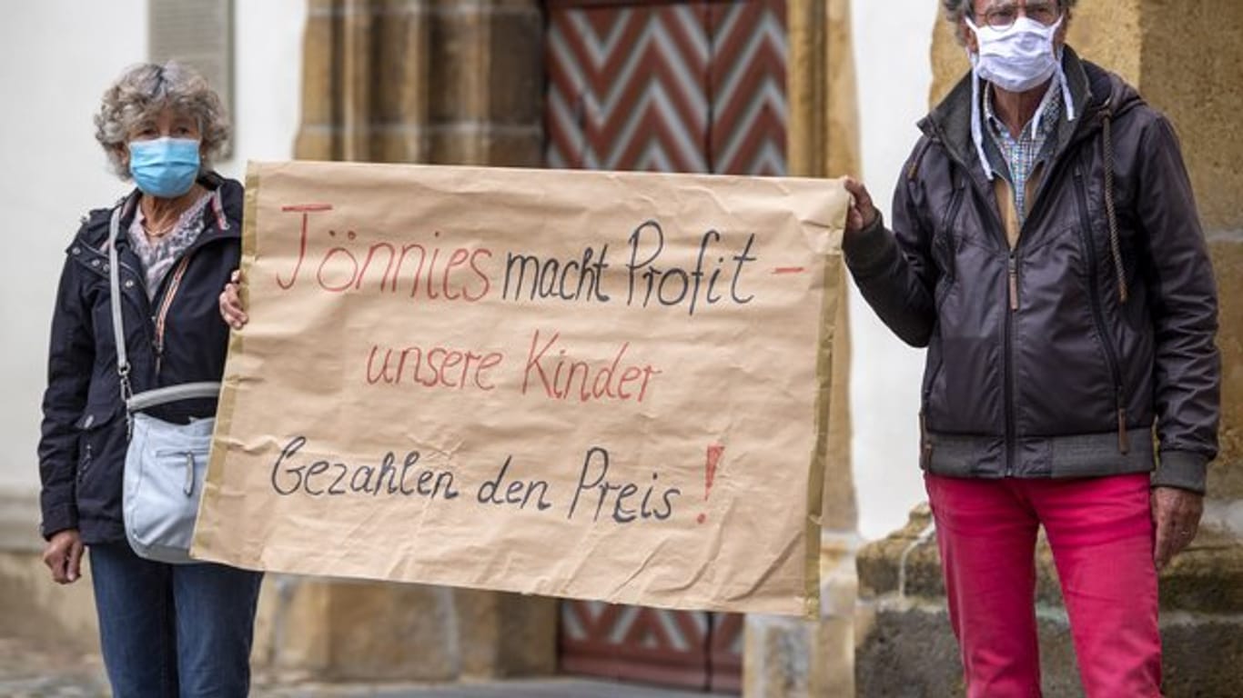Demonstranten halten während einer Mahnwache zur Situation beim Fleischwerk Tönnies auf dem Marktplatz in Rheda-Wiedenbrück ein Schild mit der Aufschrift "Tönnies macht Profit - unsere Kinder bezahlen den Preis!".