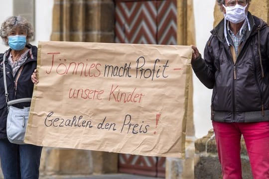 Demonstranten halten während einer Mahnwache zur Situation beim Fleischwerk Tönnies auf dem Marktplatz in Rheda-Wiedenbrück ein Schild mit der Aufschrift "Tönnies macht Profit - unsere Kinder bezahlen den Preis!".