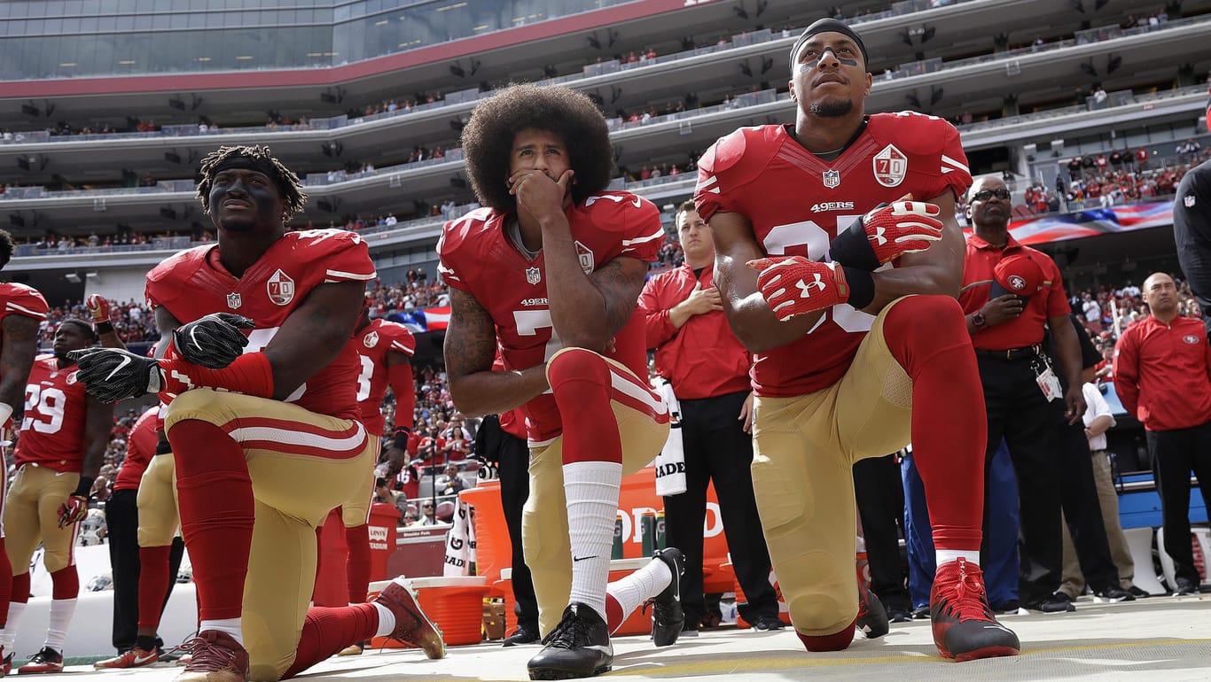Die NFL Profis Eli Harold (l.), Colin Kaepernick (m.) und Eric Reid (r.) der San Francisco 49ers knien während der Nationalhymne bei einem NFL-Spiel gegen die Dallas Cowboys.