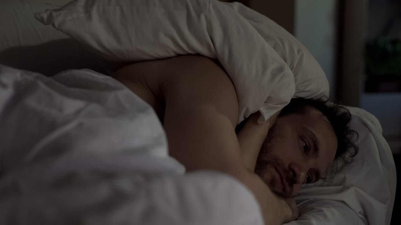 Ein Mann liegt wach im Bett: Schlafstörungen sind typische Begleiterscheinungen von Depressionen.