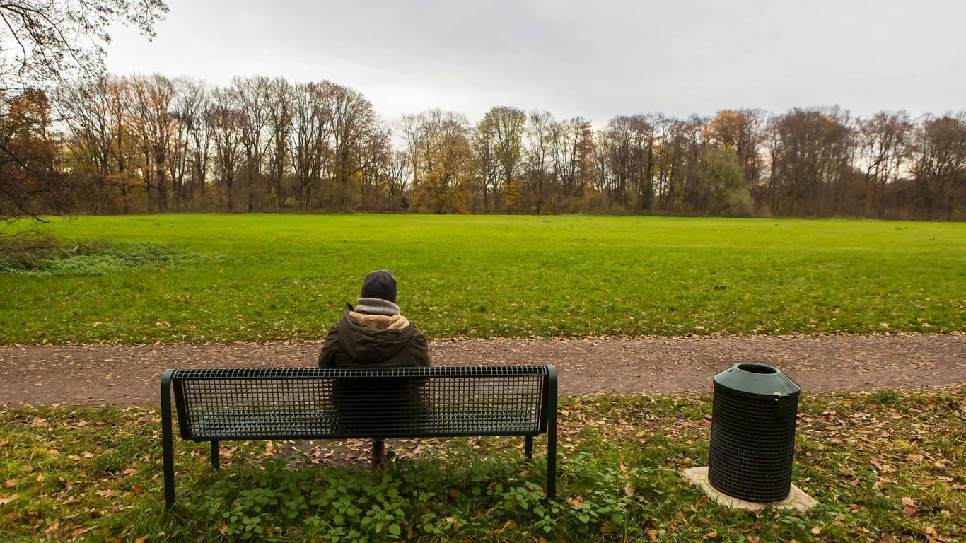 Eine Person sitzt auf einer Bank an der Gleueler Wiese in Köln: Der 1. FC darf dort sein umstrittenes neues Leistungszentrum bauen.