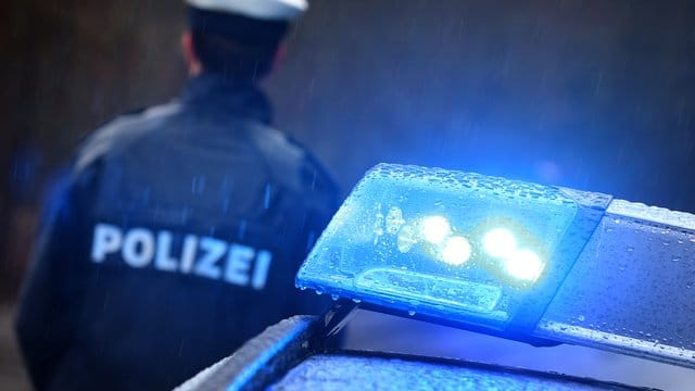 Ein Polizist steht im Regen vor einem Streifenwagen mit Blaulicht: Beamte fanden eine Leiche im Haus eines Bruchsalers.