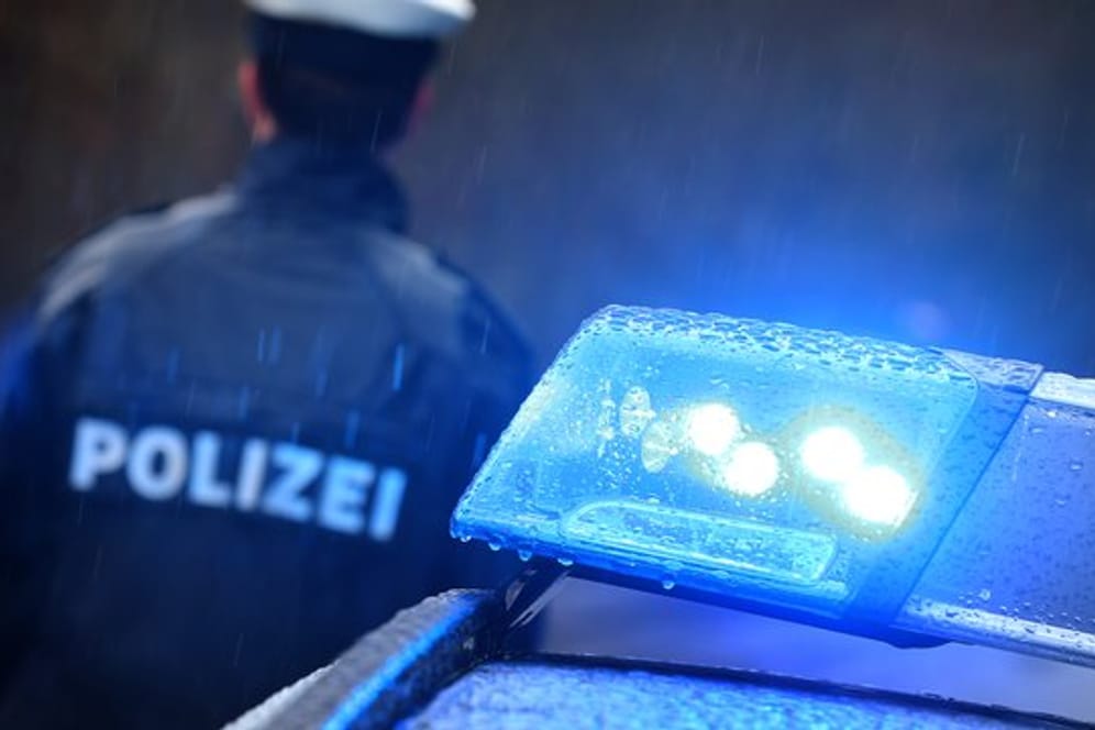 Ein Polizist steht im Regen vor einem Streifenwagen mit Blaulicht: Beamte fanden eine Leiche im Haus eines Bruchsalers.