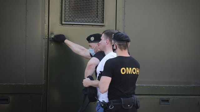 Polizeibeamte mit Mundschutzmasken halten während einer Kundgebung in Minsk einen Demonstranten fest. Polizeibeamte mit Mundschutzmasken halten während einer Kundgebung in Minsk einen Demonstranten fest.