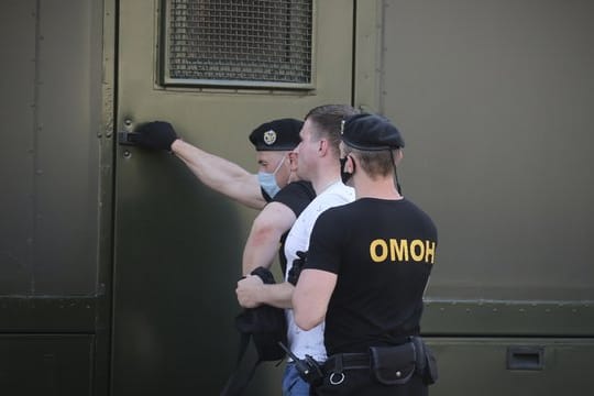 Polizeibeamte mit Mundschutzmasken halten während einer Kundgebung in Minsk einen Demonstranten fest.