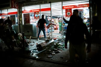 Menschen stehen vor einem geplünderten Geschäft in der Marienstraße: Viele Polizisten wurden bei der Randale in Stuttgart verletzt.
