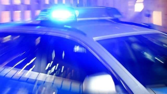 Ein Streifenwagen der Polizei steht mit eingeschaltetem Blaulicht auf der Straße (Symbolbild): Ein Mann ist in einem Fahrstuhl steckengeblieben und hat Beamten attackiert.