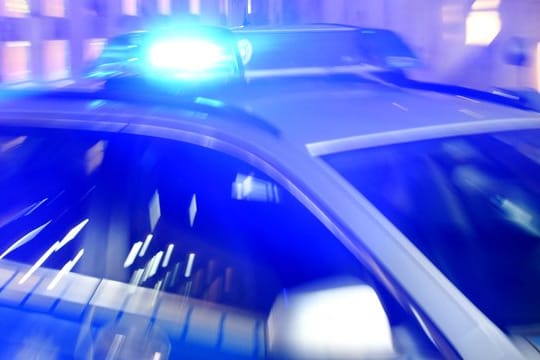 Ein Streifenwagen der Polizei steht mit eingeschaltetem Blaulicht auf der Straße (Symbolbild): Ein Mann ist in einem Fahrstuhl steckengeblieben und hat Beamten attackiert.