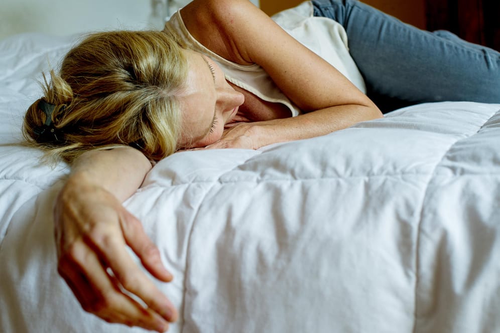 Eine Frau liegt auf dem Bett: Viele Depressive klagen über Morgen-Tiefs. Sie fühlen sich müde und erschöpft nach dem Aufwachen.