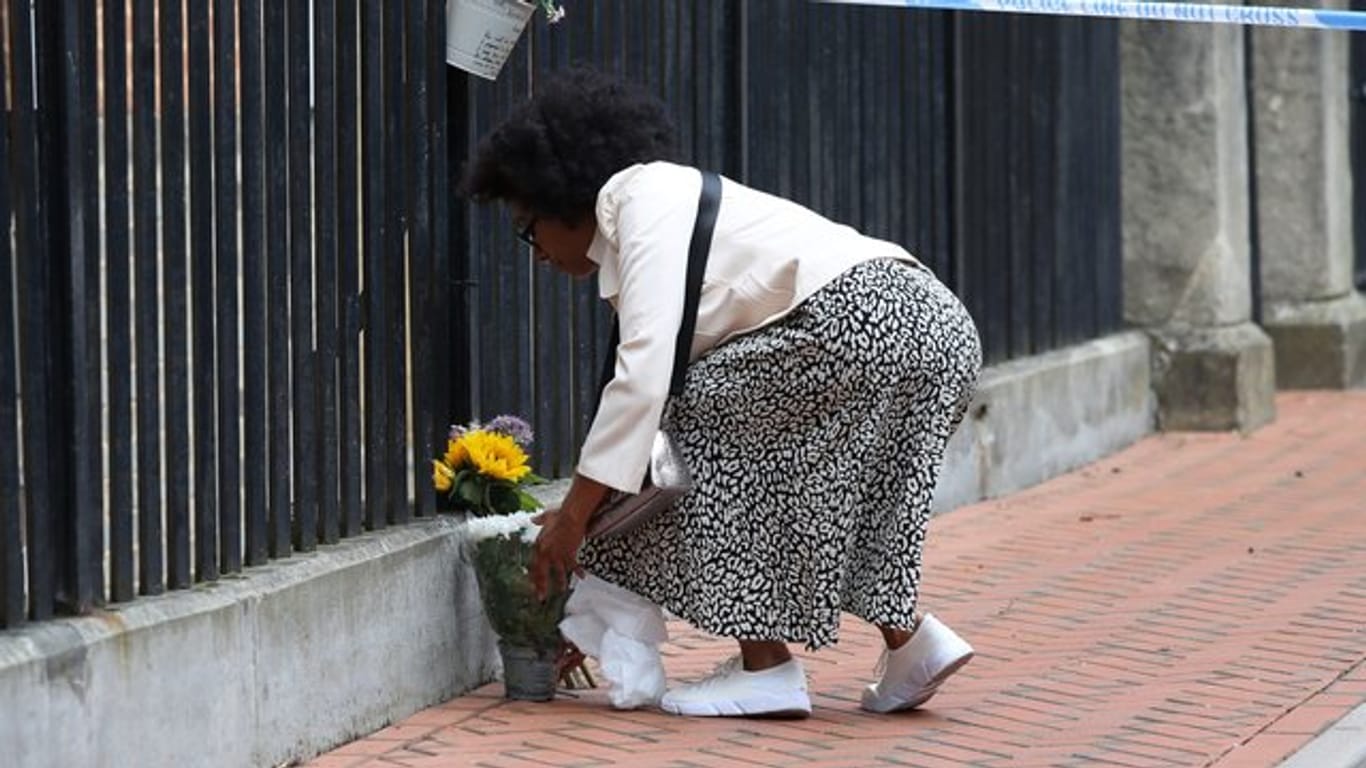 Eine Frau legt zum Gedenken an die Opfer im Stadtzentrum von Reading Blumen nieder.