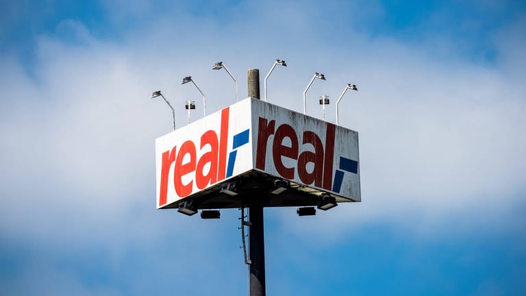 Das Logo von Real (Symbolbild): Die Konkurrenz teilt sich einzelne Teile der Supermarktkette unter sich auf.