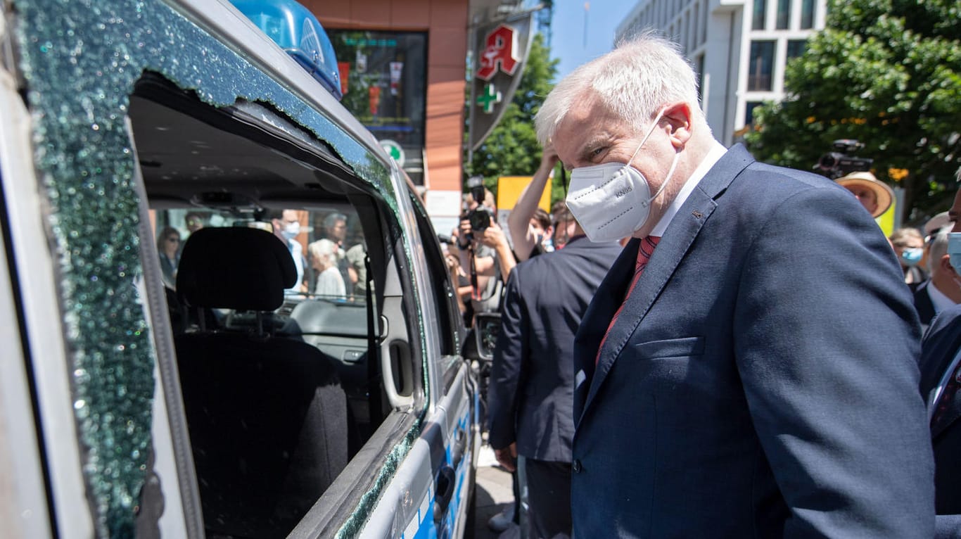 Bundesinnenminister Horst Seehofer (CSU) betrachtet während seines Besuchs ein Polizeiauto, das während der nächtlichen Randale beschädigt wurde.