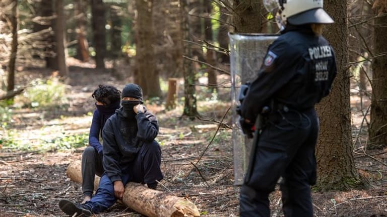 Ein Polizistin im Hambacher Wald vor zwei Umweltaktivisten.