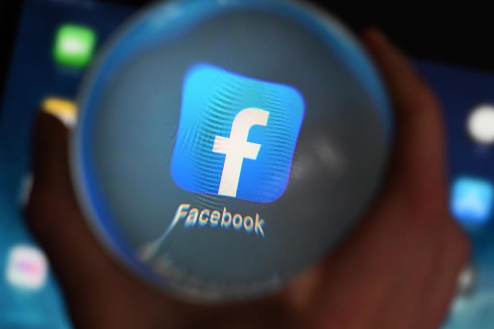 Eine Person schaut durch eine Glaskugel auf einem Tablet auf die Facebook App: Am 23.06.2020 will der Bundesgerichtshof (BGH) im Streit zwischen Facebook und dem Bundeskartellamt wegen der Sammlung von Nutzerdaten verhandeln.