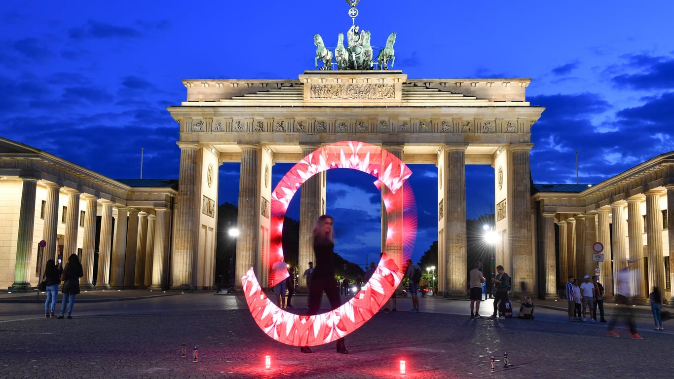 Eine Lichtkünstlerin performt mit roten Lichtern vor dem Brandenburger Tor: Auch das berühmte Berliner Wahrzeichen war Teil der "Night of Light".