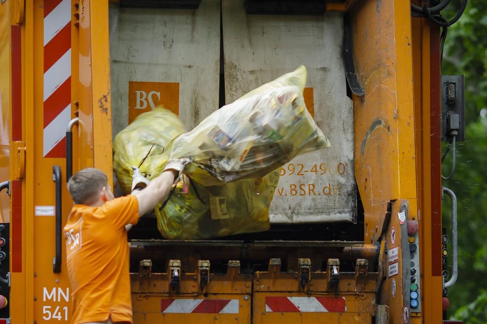 Ein Müllwerker wirft gelbe Säcke in ein Müllauto: Das Müllaufkommen ist in der Coronakrise gestiegen.