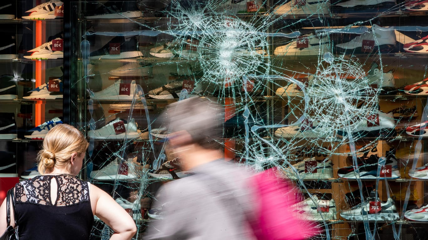 Fußgänger gehen an einem schwer beschädigten Schaufenster eines Geschäfts in der Stuttgarter Königstraße vorbei: Mittlerweile hat die Polizei 26 Tatverdächtige ermitteln können.
