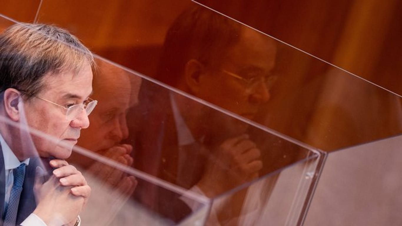 Armin Laschet sitzt in einer Box aus Plexiglas im Plenum des Landtags.