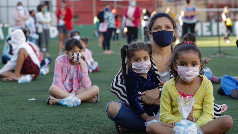 Eine Familie sitzt auf einem Fußballfeld in der Favela Paraisopolis in Sao Paulo: Die Neuinfektionen in dem lateinamerikanischen Land steigen weiter rasant an.