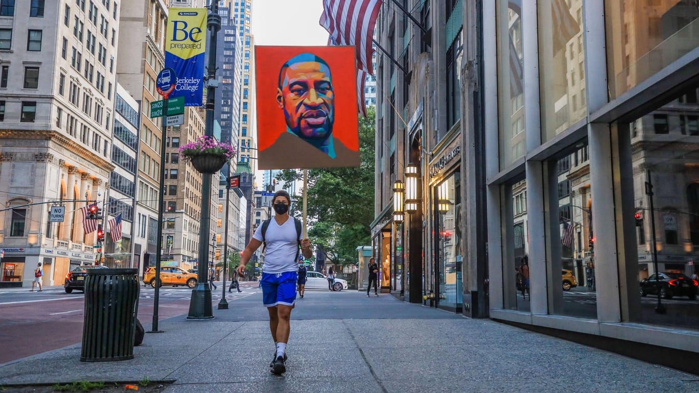 Ein Mann läuft durch die Straßen New Yorks, Floyds Gesicht auf einem Poster über ihm: Die Tötung des Afroamerikaners löste weltweite Proteste gegen Rassismus aus.