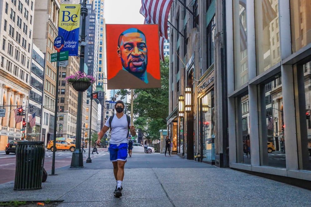Ein Mann läuft durch die Straßen New Yorks, Floyds Gesicht auf einem Poster über ihm: Die Tötung des Afroamerikaners löste weltweite Proteste gegen Rassismus aus.