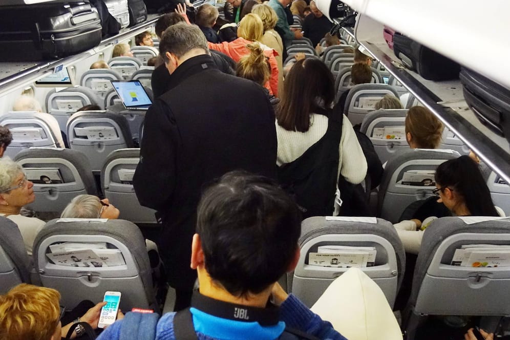 Menschen in einer Flugzeugkabine: Nicht alle Sitze sind gleich hoch mit Keimen belastet.