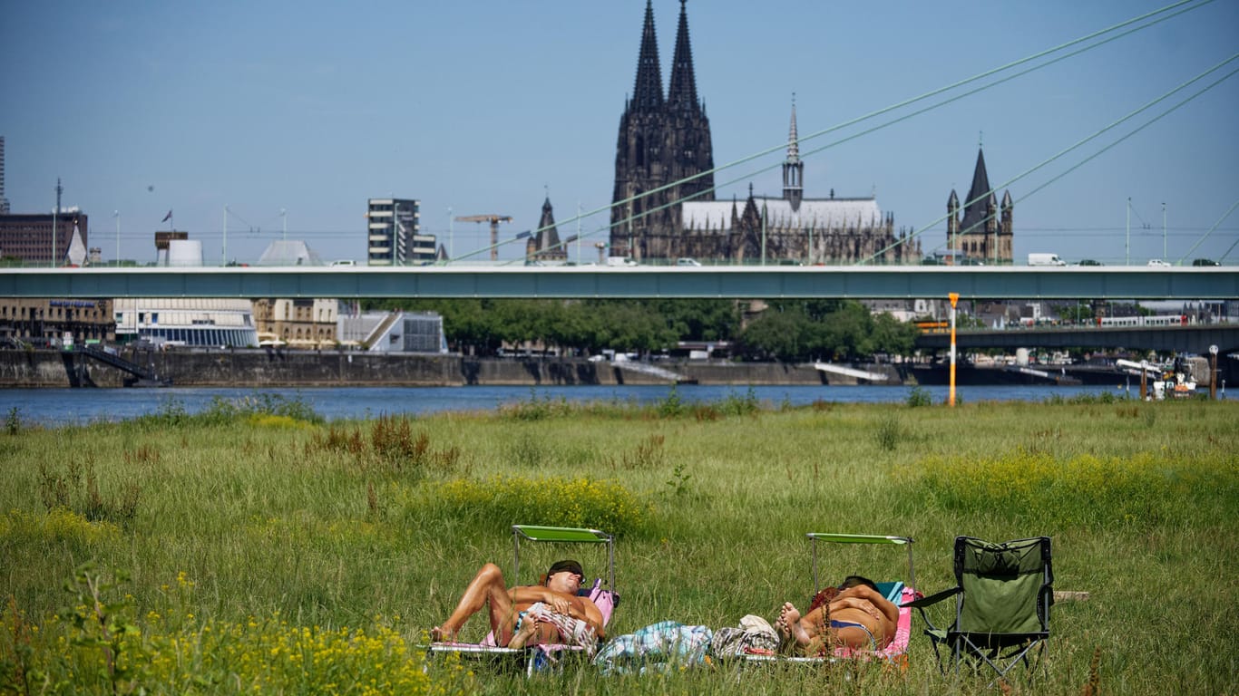 Zwei Männer genießen auf den Poller Wiesen am Rheinufer die Sonne: In Köln war es am Mittwoch besonders warm.