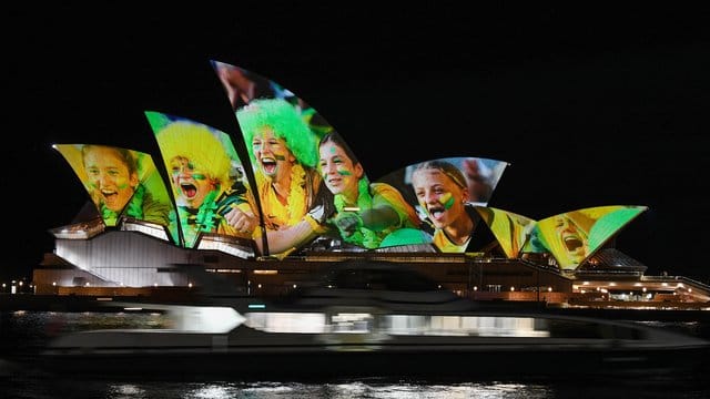 Australien und Neuseeland sind die Gastgeber der Frauenfußball-Weltmeisterschaft 2023: Das Opernhaus wird mit leuchtenden bunten Fotos von Fußball-Fans angestrahlt. Australien und Neuseeland sind die Gastgeber der Frauenfußball-Weltmeisterschaft 2023: Das Opernhaus wird mit leuchtenden bunten Fotos von Fußball-Fans angestrahlt.