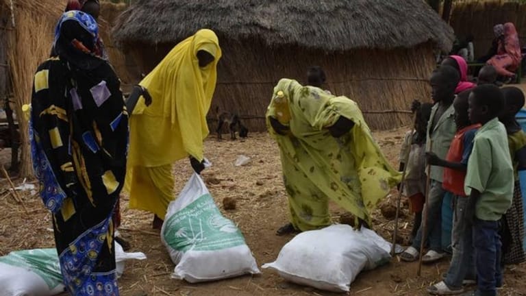 Drei Frauen nehmen im Sudan Spenden einer humanitären Organisation entgegen.