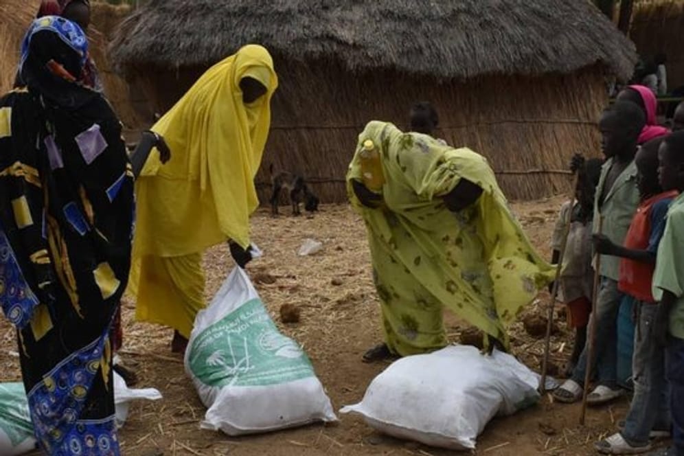 Drei Frauen nehmen im Sudan Spenden einer humanitären Organisation entgegen.