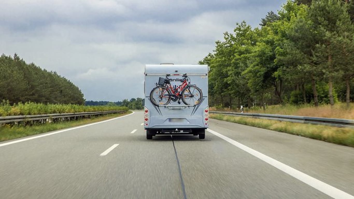 Ein Wohnmobil mit Fahrrädern am Heck fährt auf der Autobahn: Die Fernstraßen könnten zum Ferienstart in NRW voll werden.