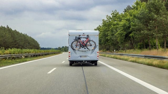 Ein Wohnmobil mit Fahrrädern am Heck fährt auf der Autobahn: Die Fernstraßen könnten zum Ferienstart in NRW voll werden. Ein Wohnmobil mit Fahrrädern am Heck fährt auf der Autobahn: Die Fernstraßen könnten zum Ferienstart in NRW voll werden.