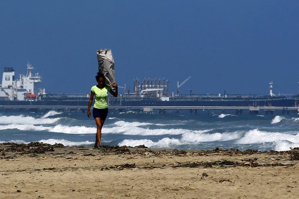 Frau am Strand von Puerto Cabello, Venezuela: Im Hintergrund ist der Öltanker Teseo zu sehen, der wegen US-Sanktionen nicht ablegt.